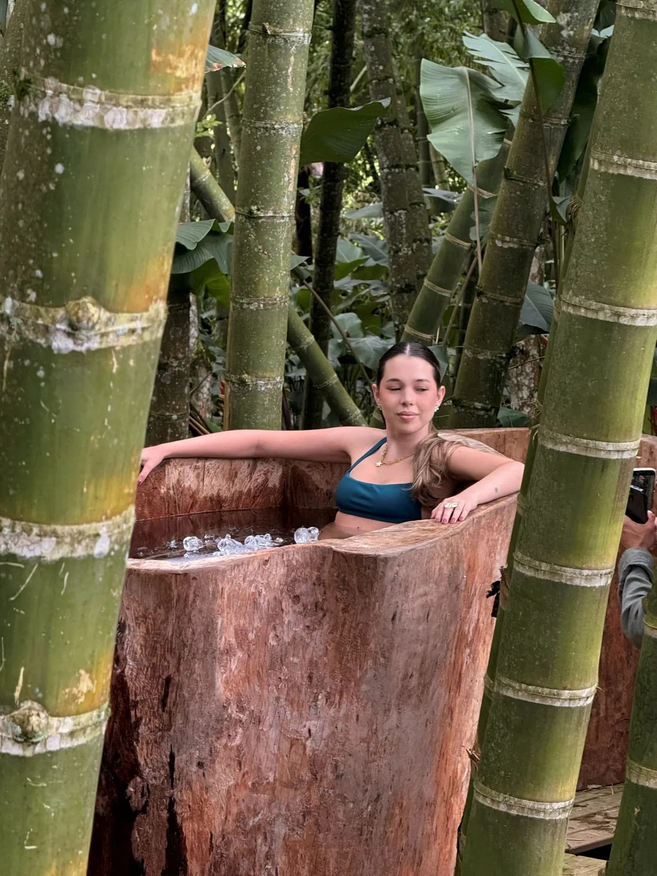 Guest inside a wooden cold-immersion tub among bamboo canes