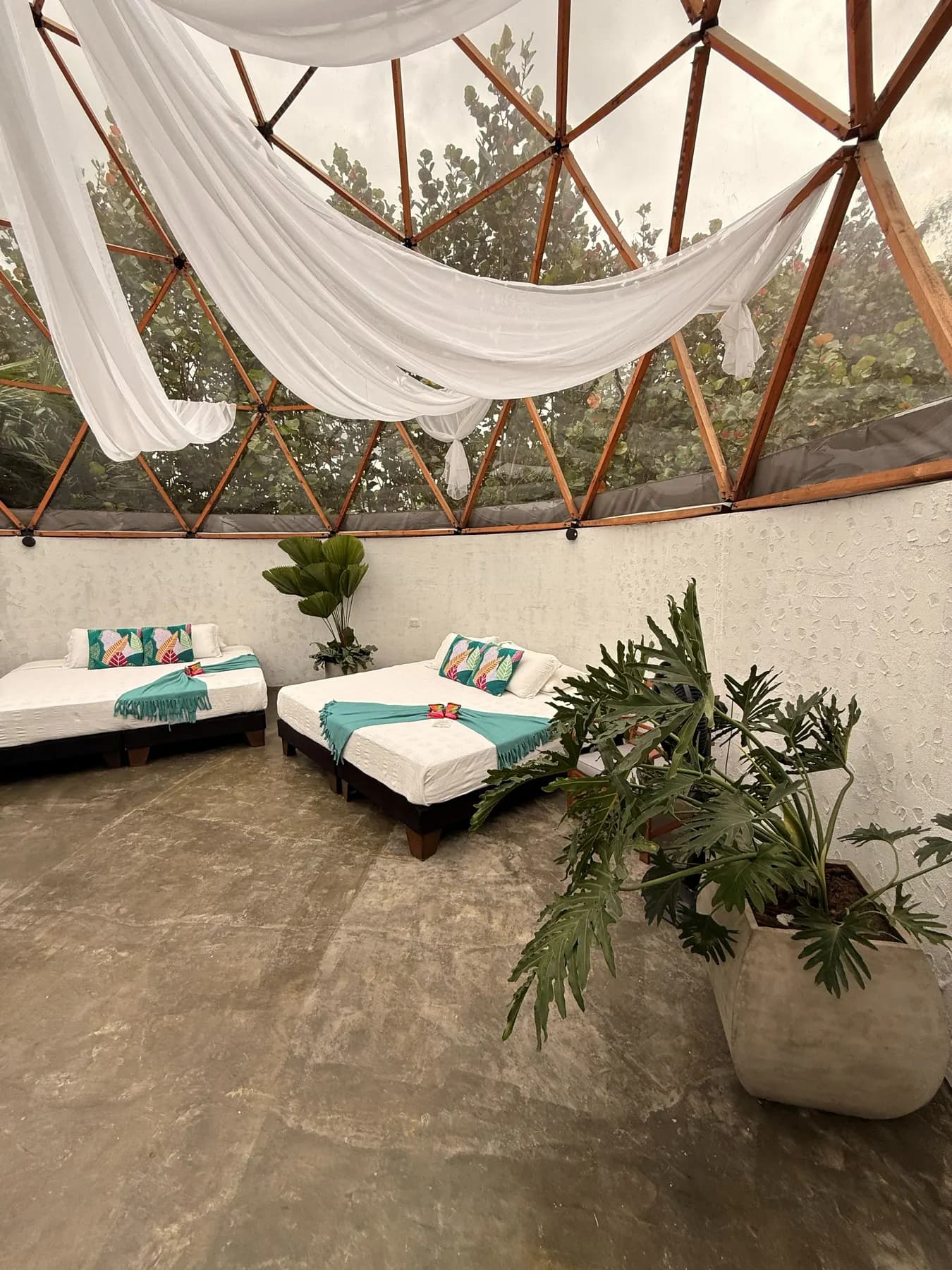 Inside the dome, white drapes hanging from the frame over beds with turquoise cushions