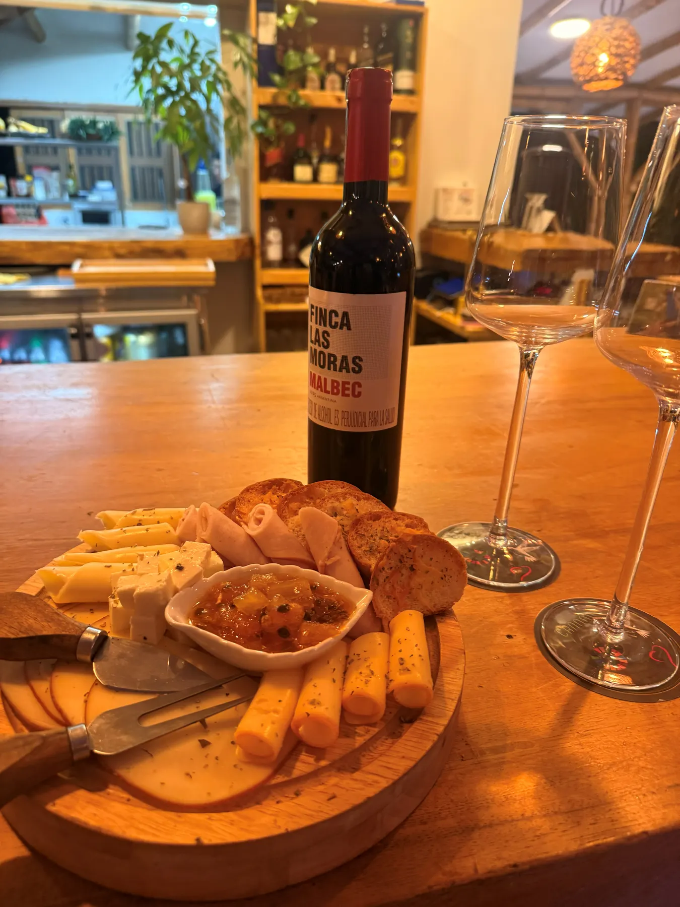 Cheese board and bread with a bottle of red wine and two glasses