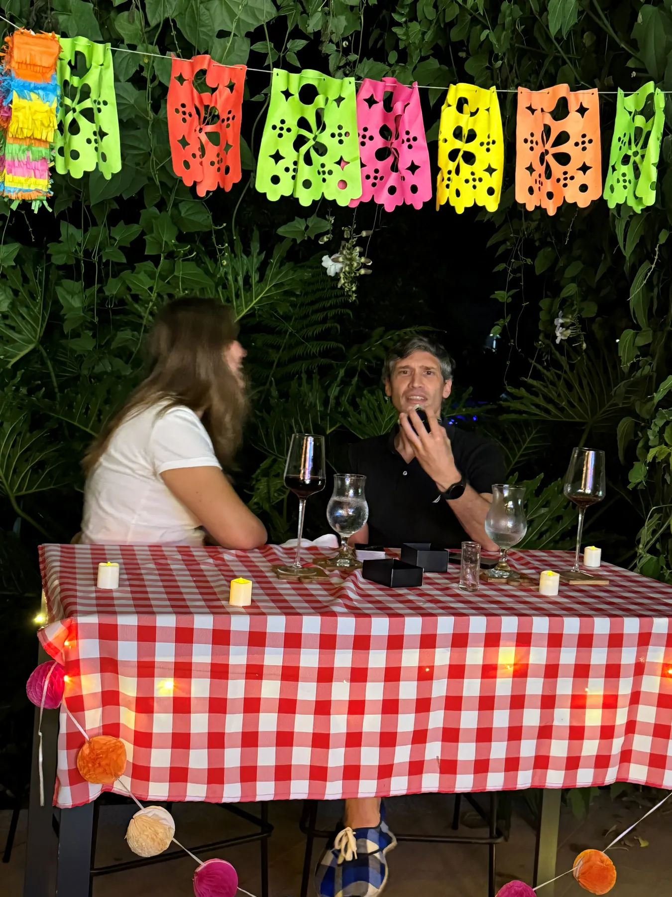 Couple dining at a checked-cloth table under colourful bunting