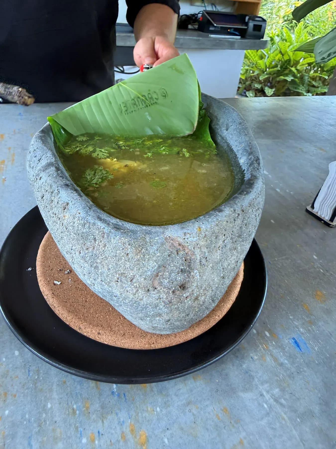 Broth served in a stone molcajete with a plantain leaf