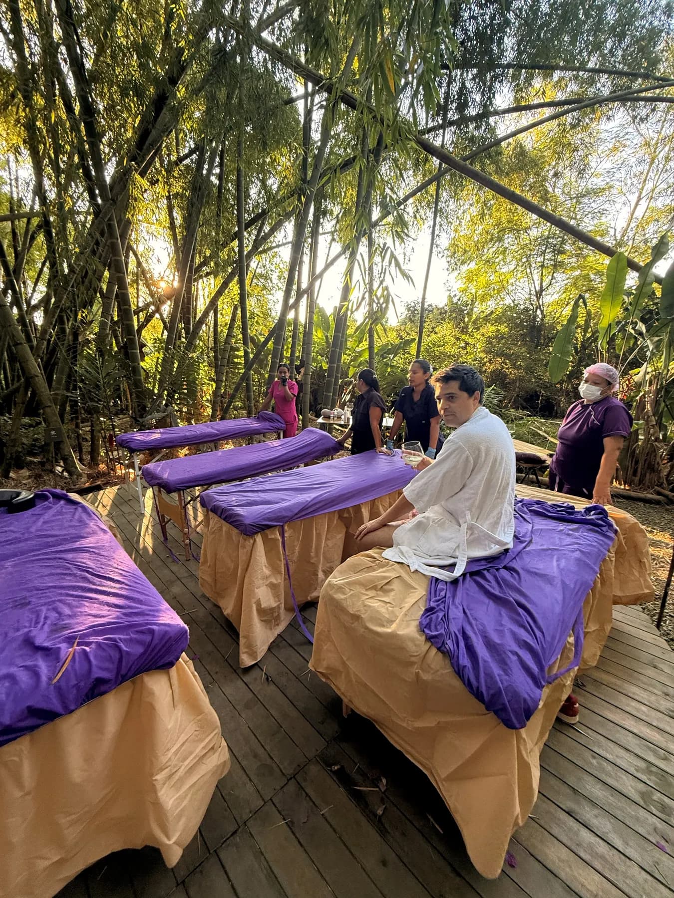 Massage tables with purple sheets under the bamboo, ready for treatment