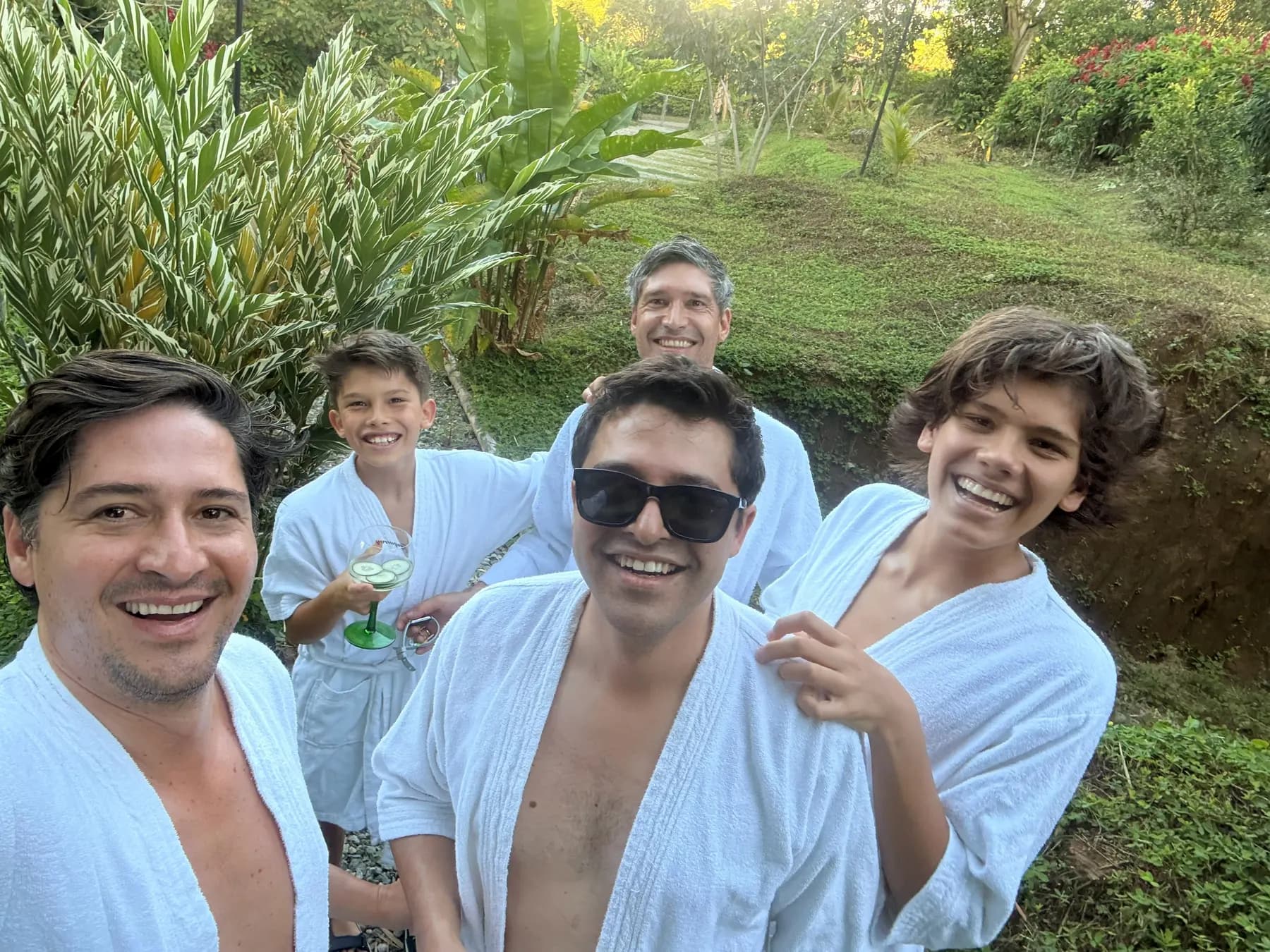 Four guests in white robes smiling in the garden after the spa