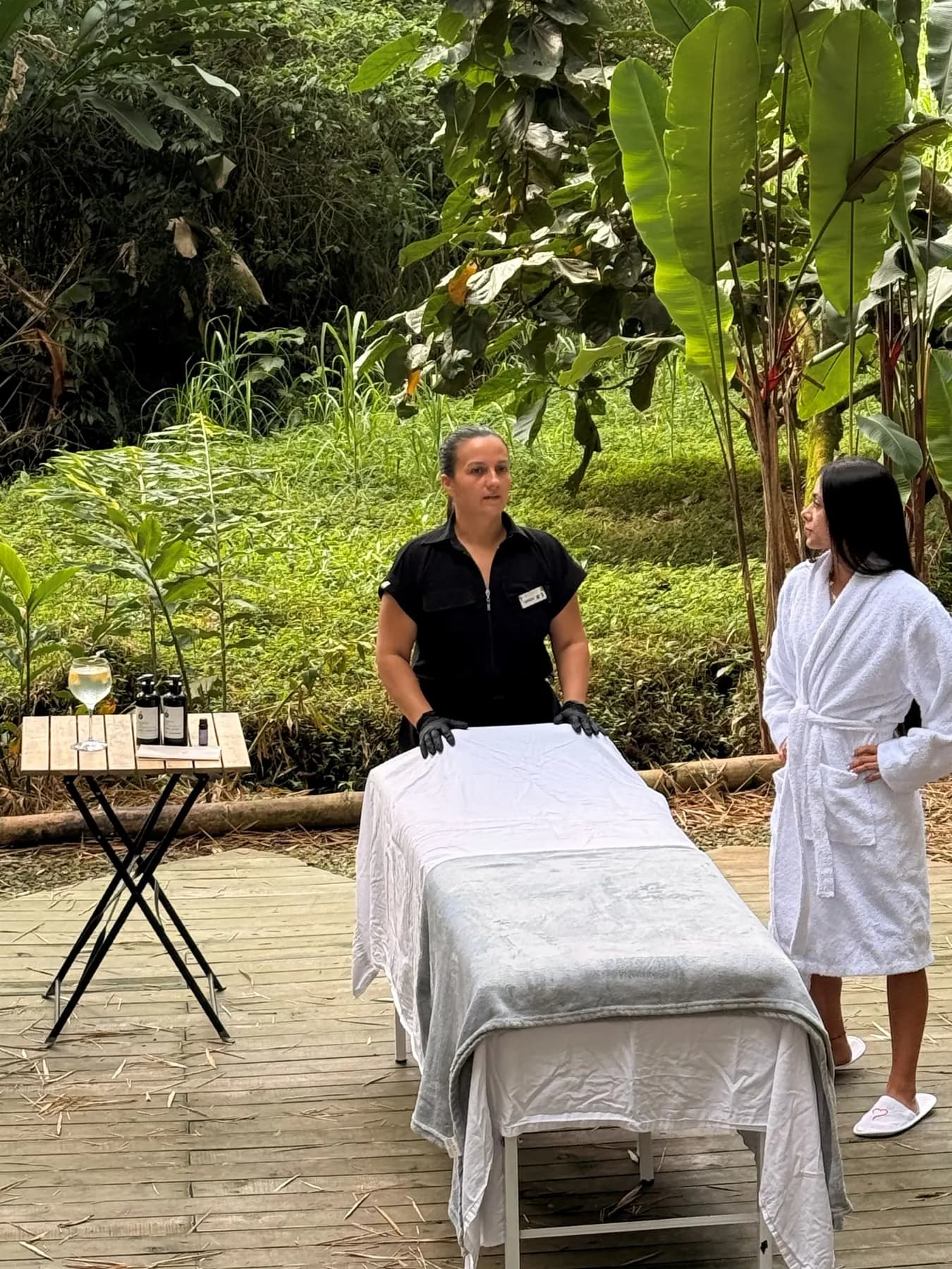 Therapist and guest beside a massage table set up on the bamboo-forest deck