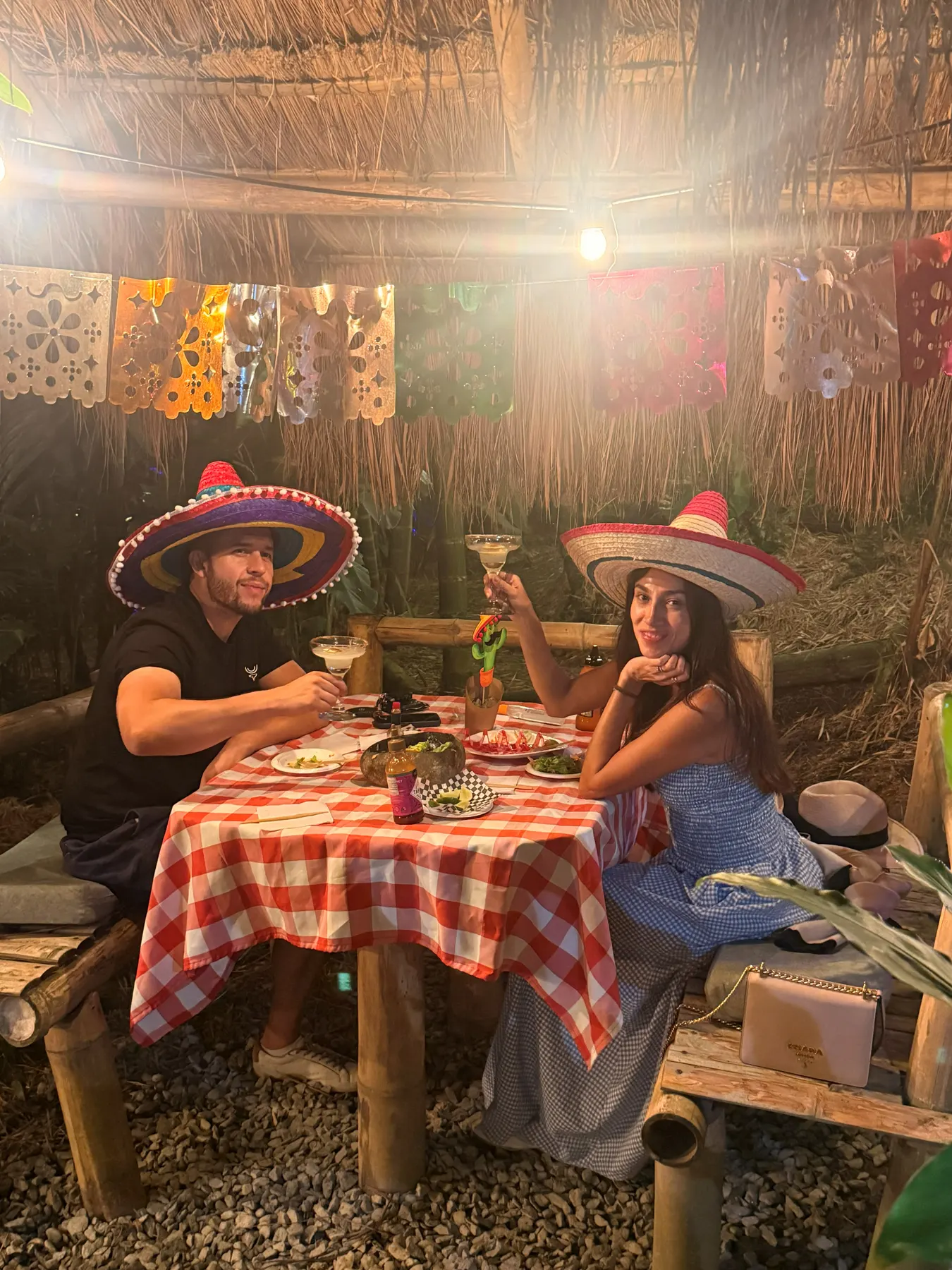 Couple in sombreros at a red checked-cloth table under the kiosk