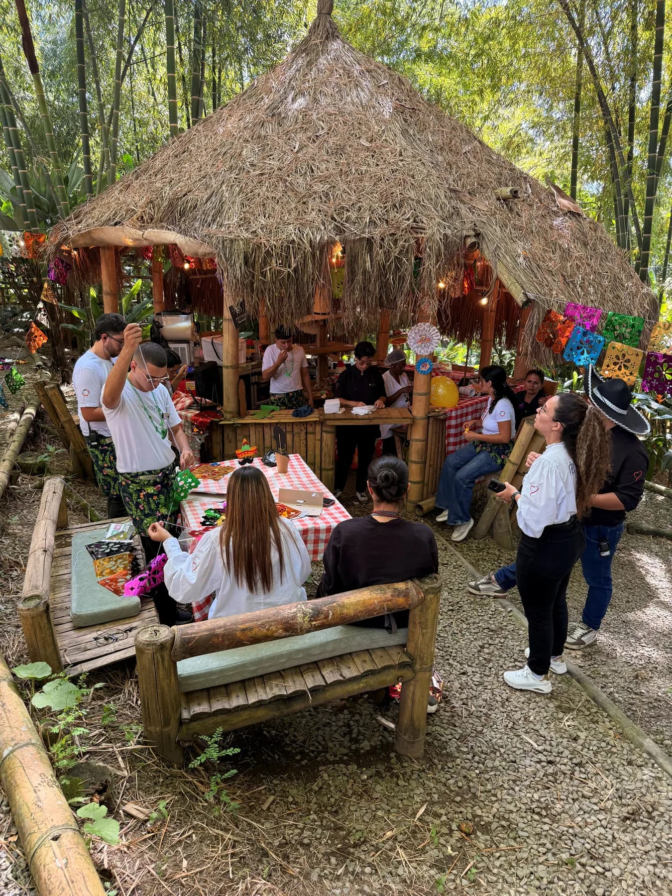 Taco Stop’s palm-thatched kiosk among bamboo, with bunting and diners
