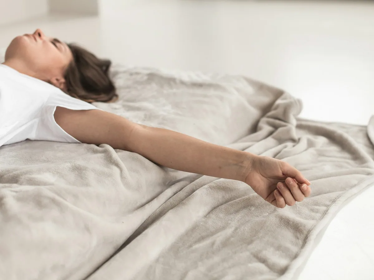A woman lying on a treatment table with her arms outstretched