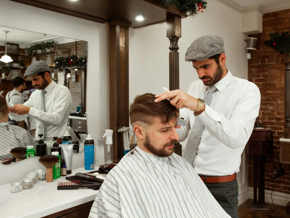 A barber cutting a client’s hair in a barbershop