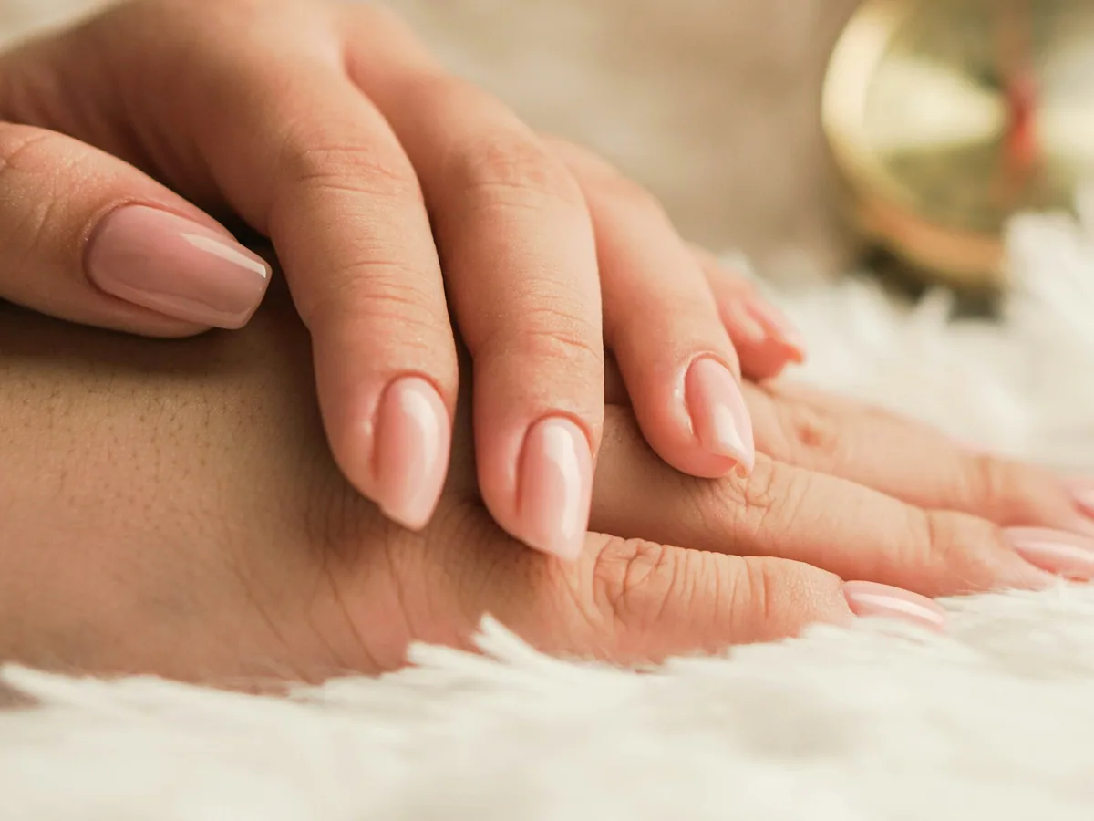 Hands with tidy nails resting on a white blanket