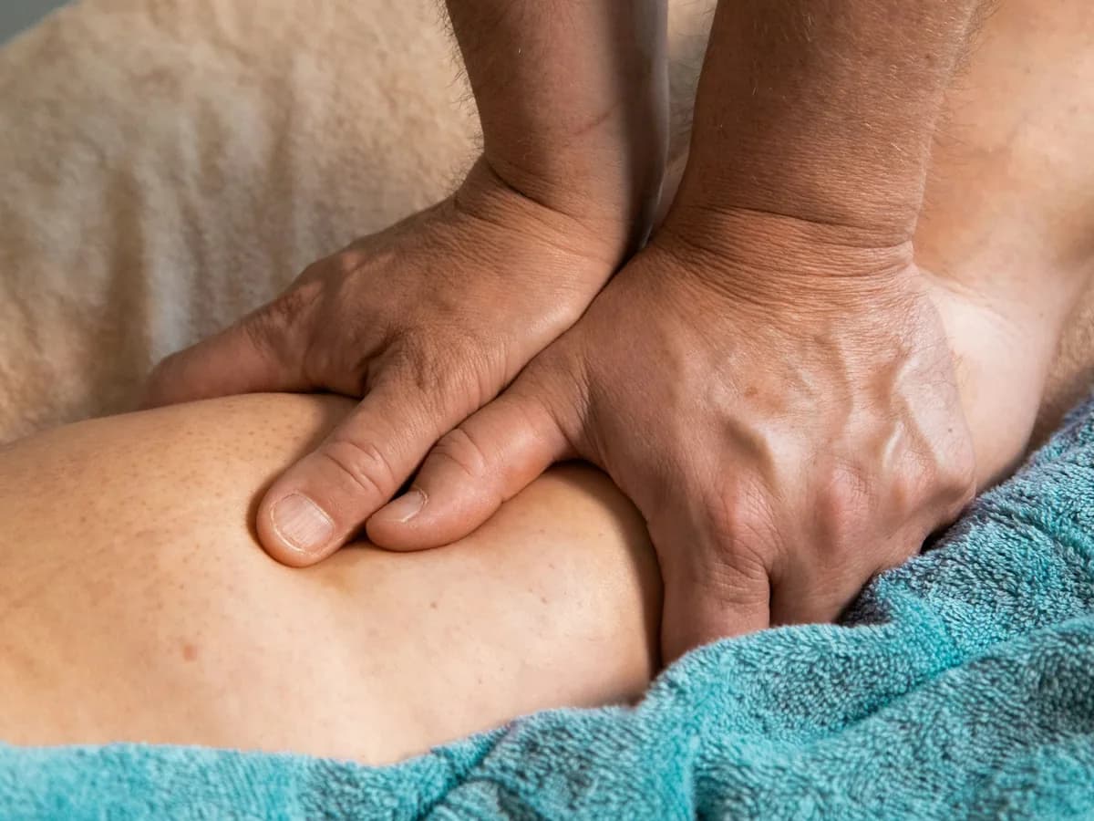 A therapist’s hands pressing into a person’s thigh