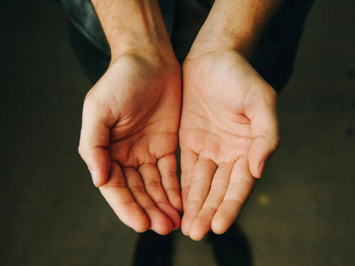 Two open hands held together against a dark ground