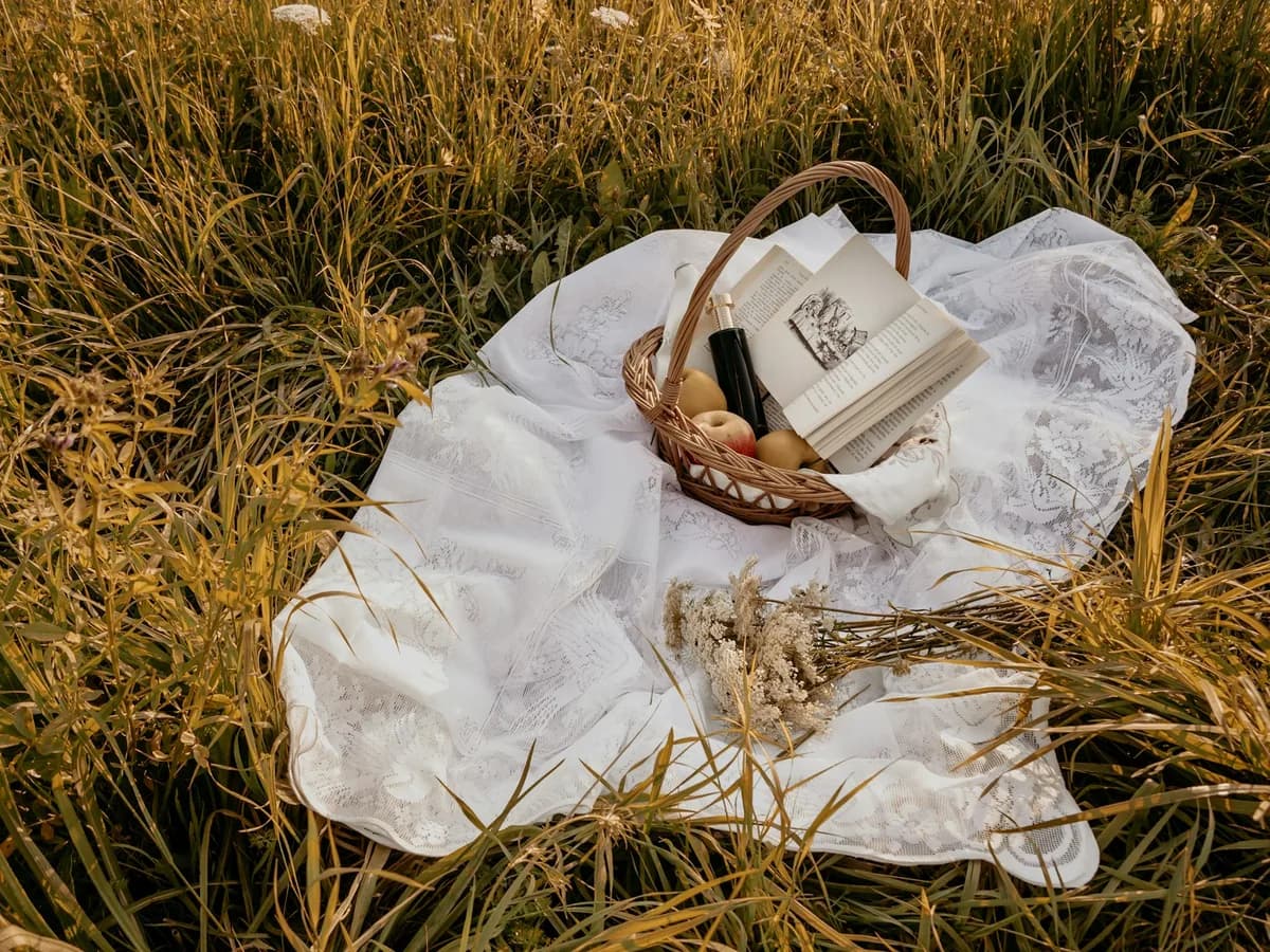 A picnic basket on a white blanket in the grass