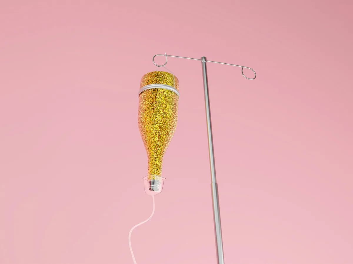 An IV bag hanging from a stand against a pink ground