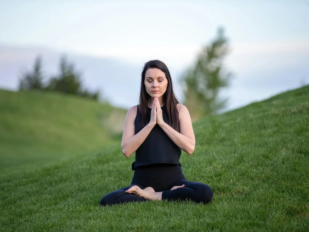 A woman meditating seated on the grass