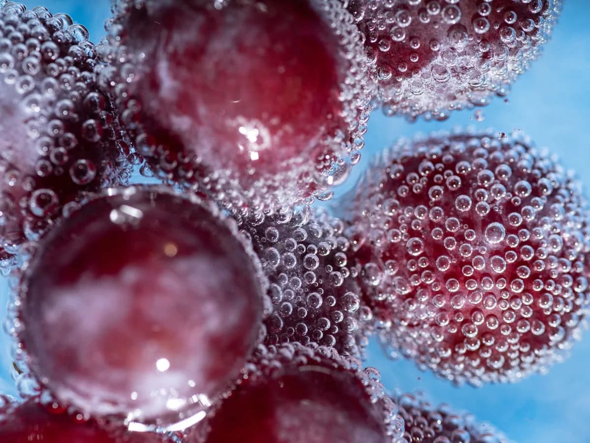 Red grapes among water bubbles, close up