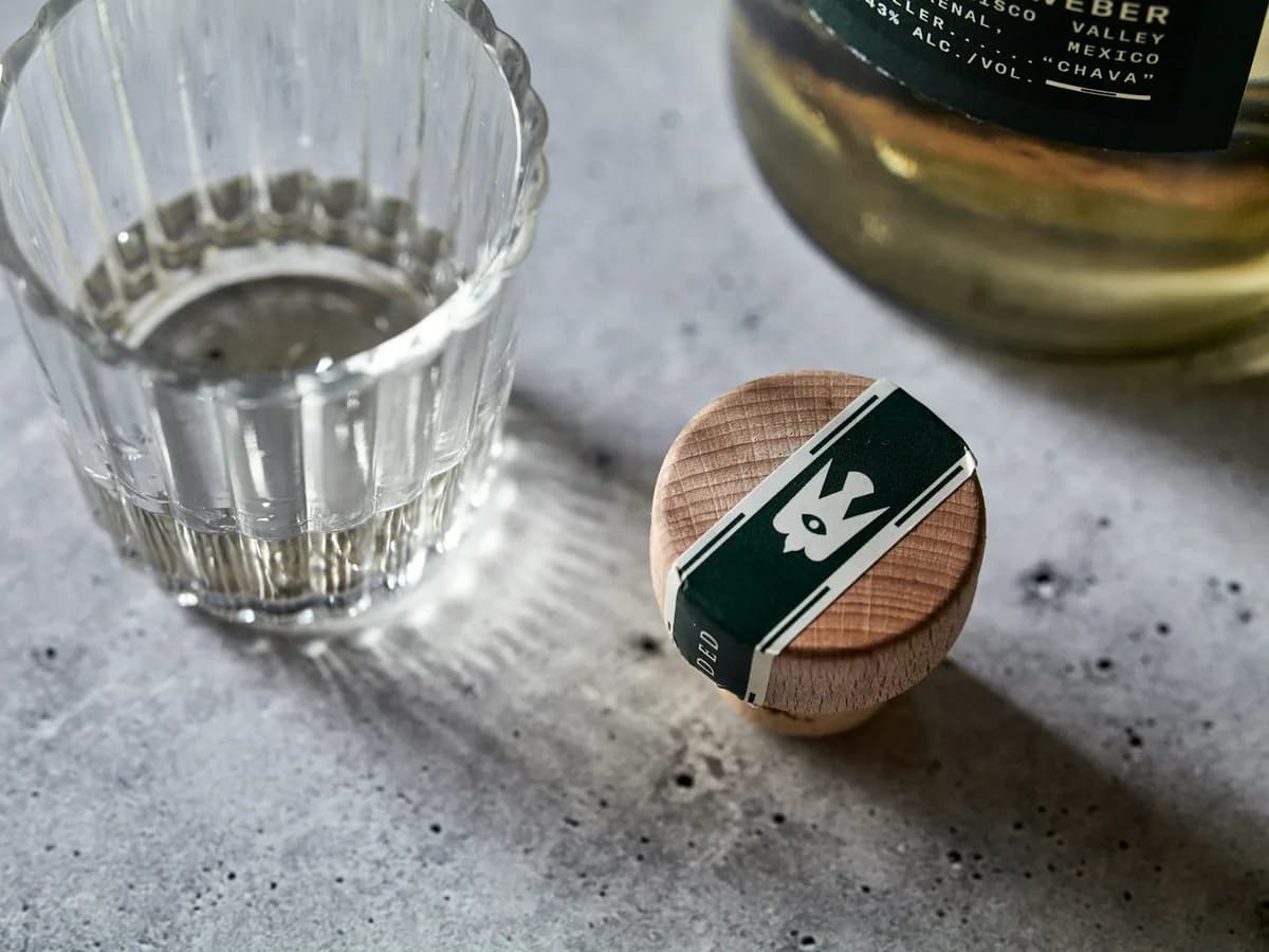 A glass of mezcal with a cork on the table