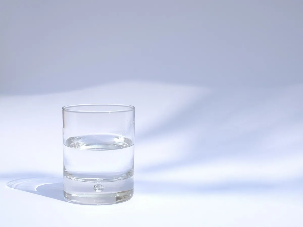 A glass of water in soft light against a pale ground
