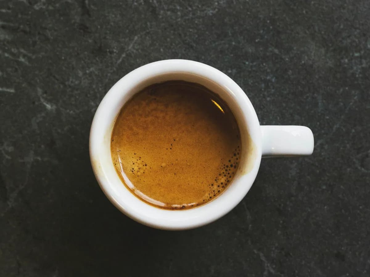 A cup of black coffee seen from above on a dark ground