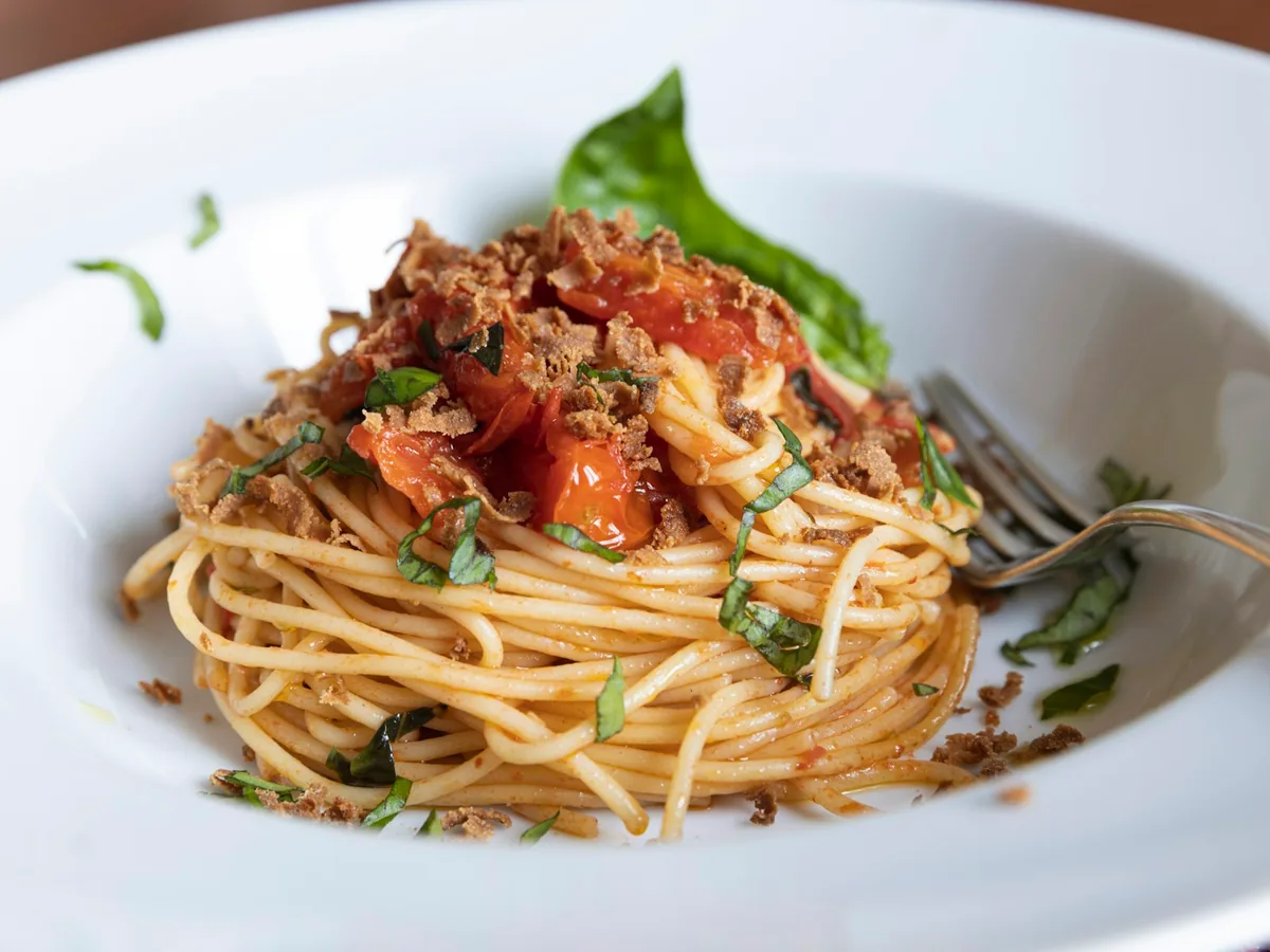 Spaghetti with bolognese sauce and basil on a white plate