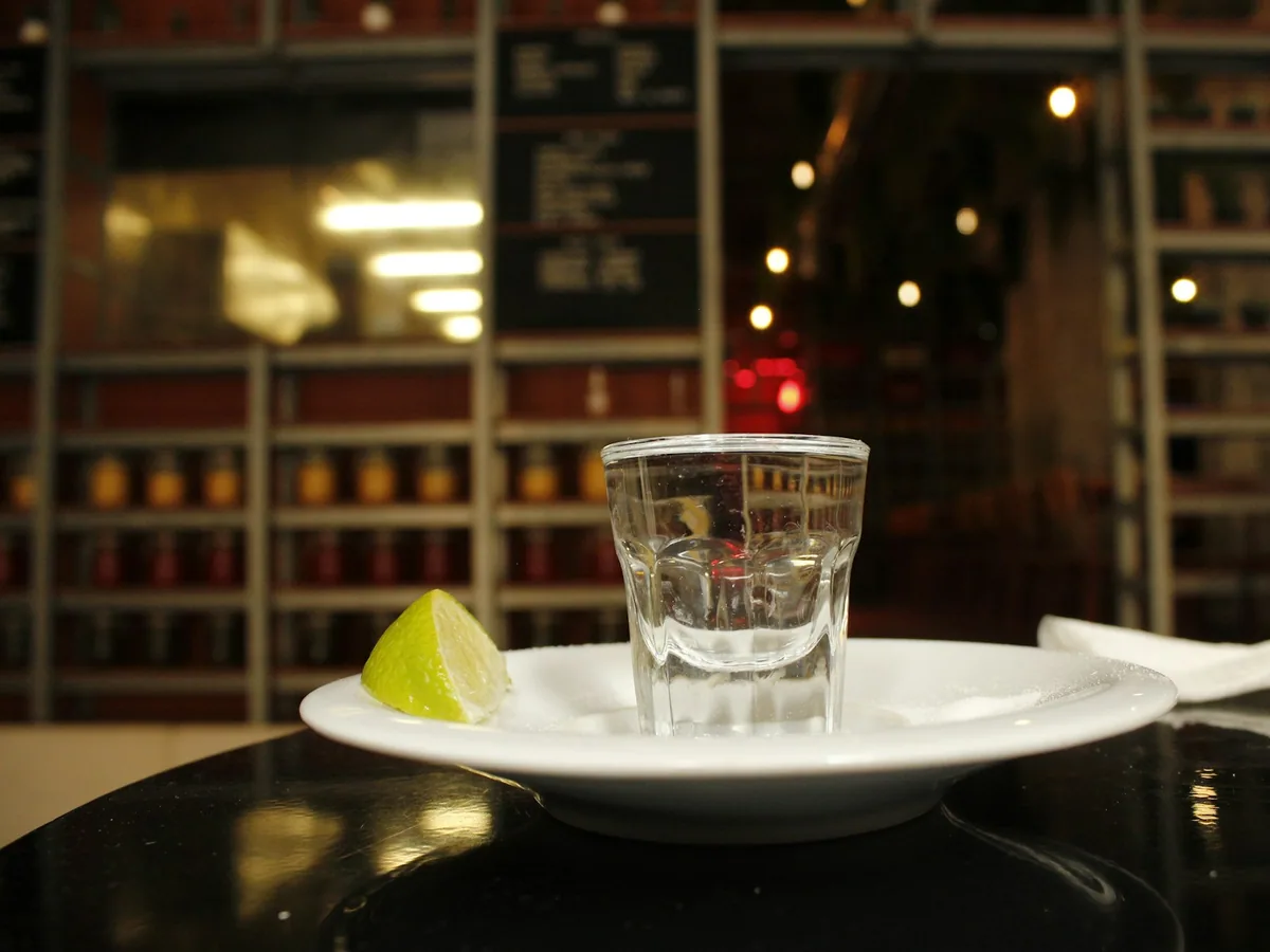 A tequila shot with lime on a plate
