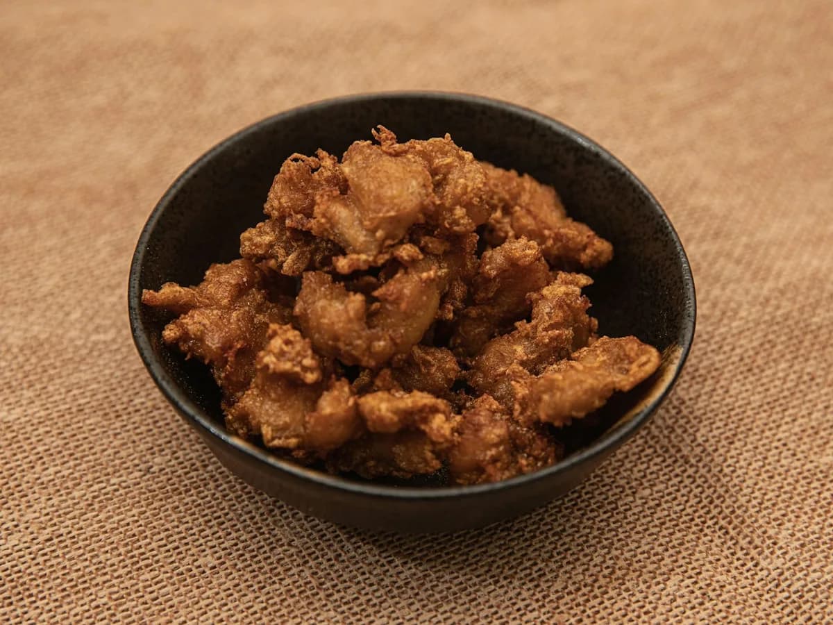 Pieces of chicharrón in a dark bowl