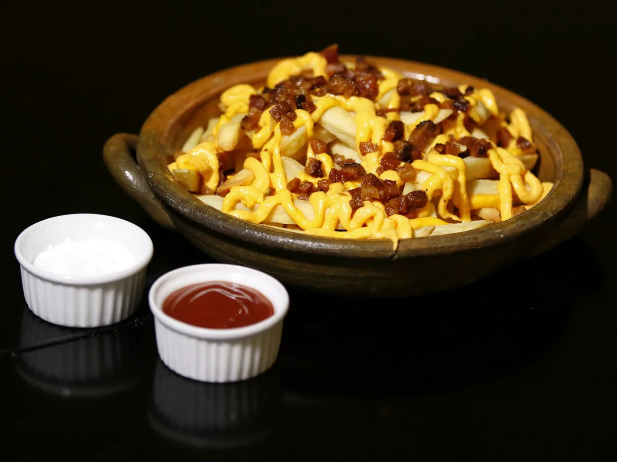 Fried potatoes with melted cheese and chorizo pieces in a bowl