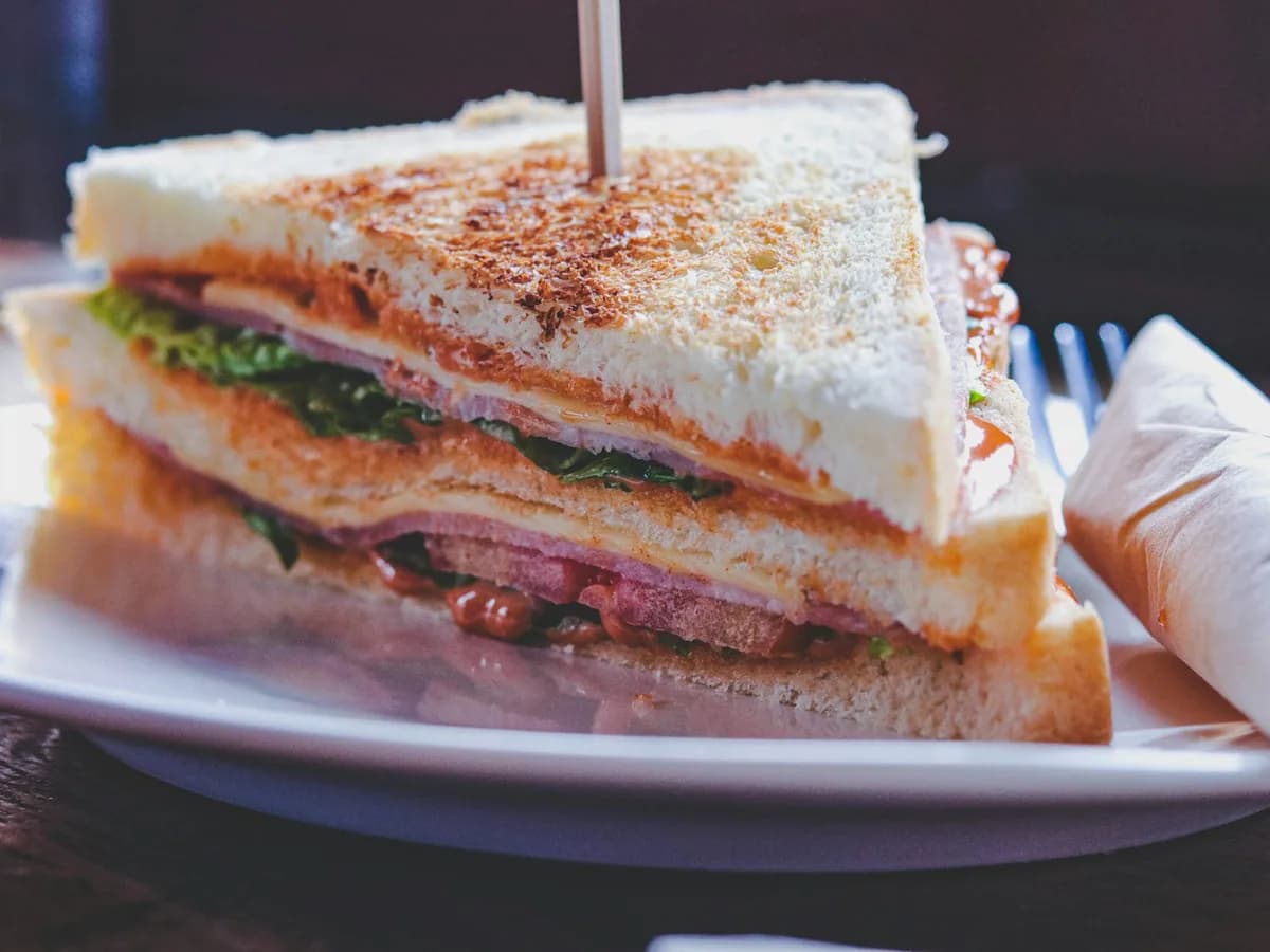 A club sandwich cut into triangles on a white plate