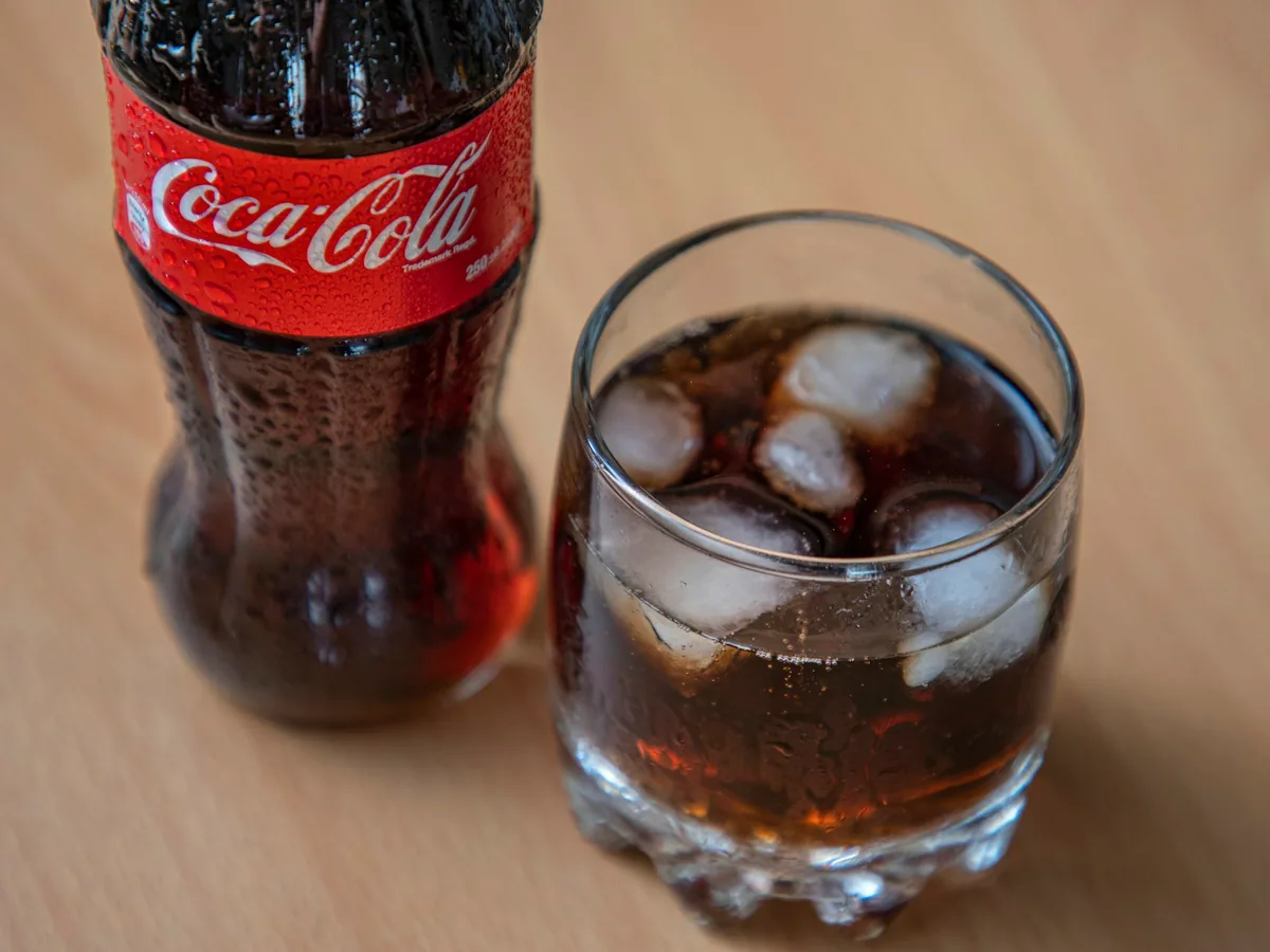 A bottle of Coca-Cola beside a glass with ice