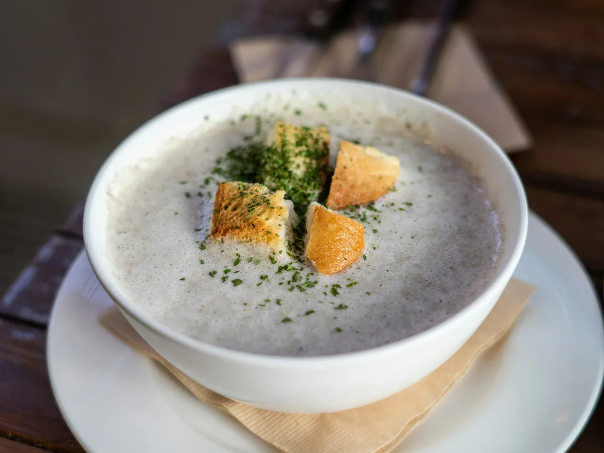 Cream of mushroom soup in a white bowl with croutons and herbs