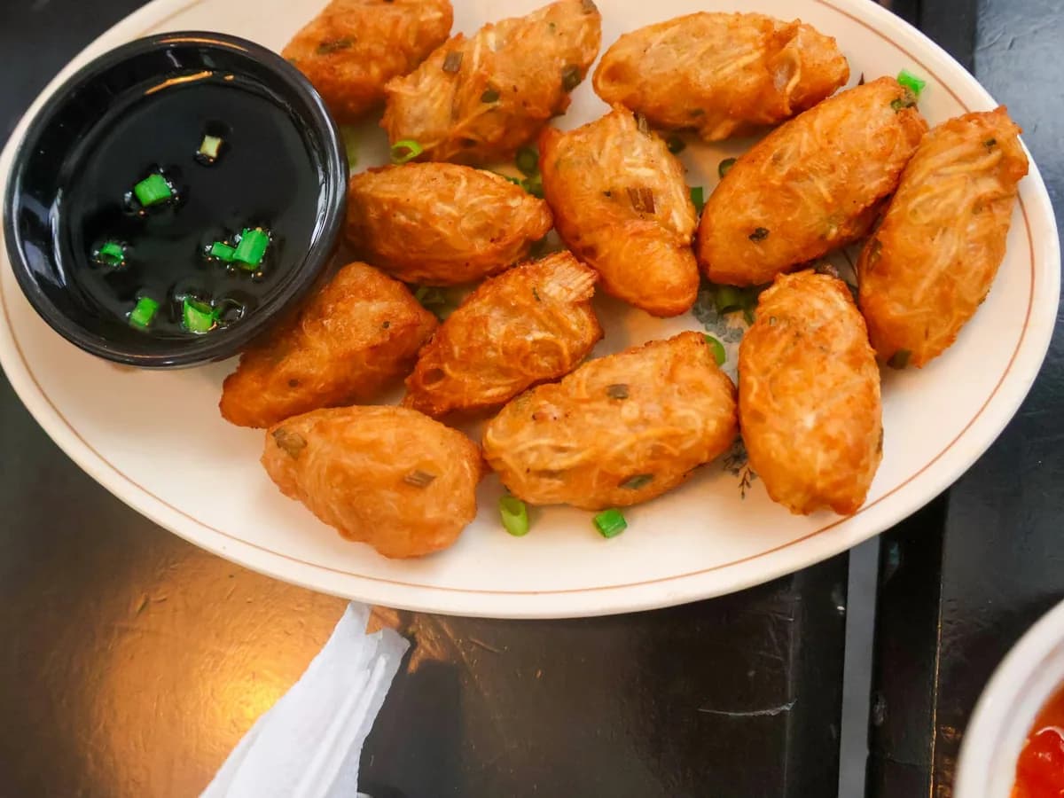 Fried croquettes on a white plate with a dipping bowl