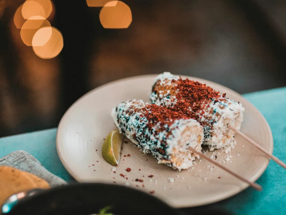 Elotes with cheese and chilli powder on a plate