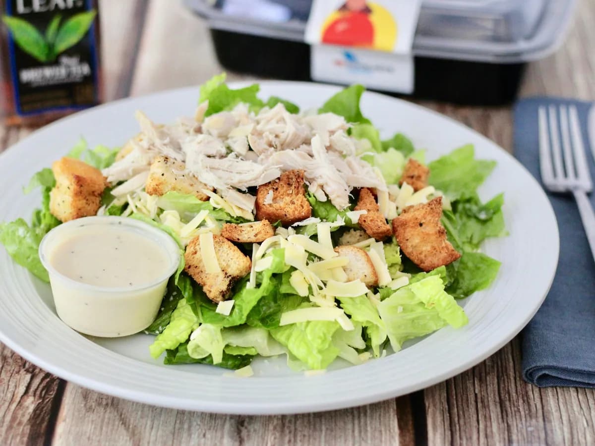 Caesar salad with chicken, croutons and parmesan on a white plate