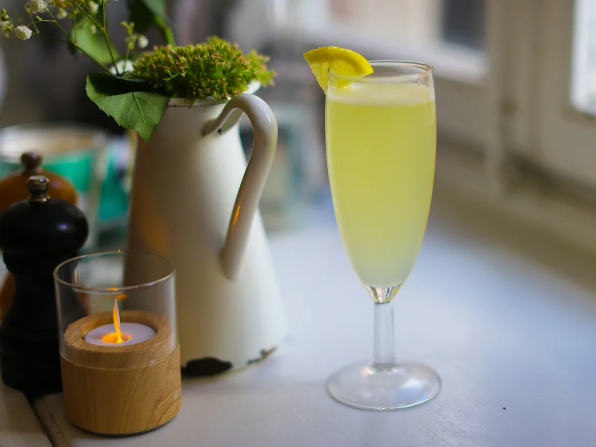 A flute glass with a pale cocktail and lemon