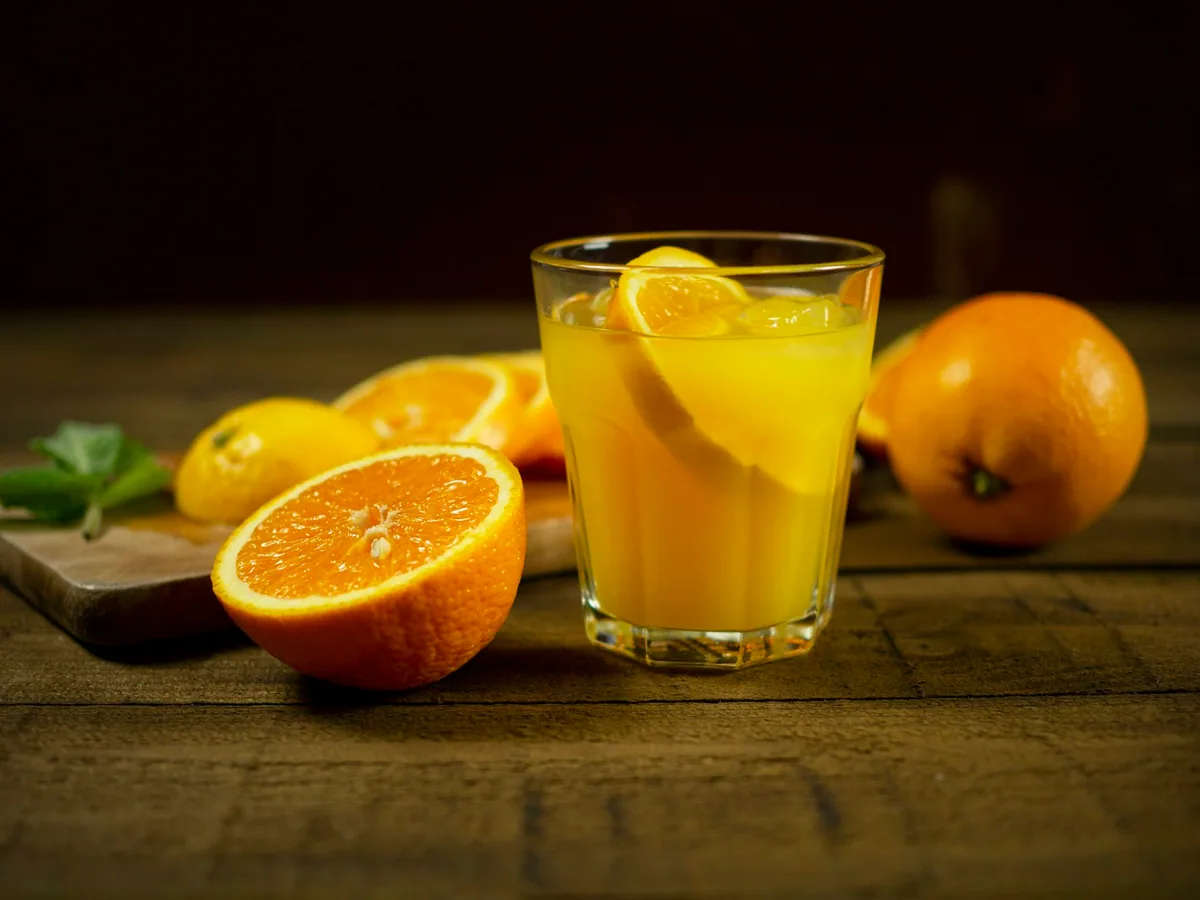 A glass of orange juice with cut oranges