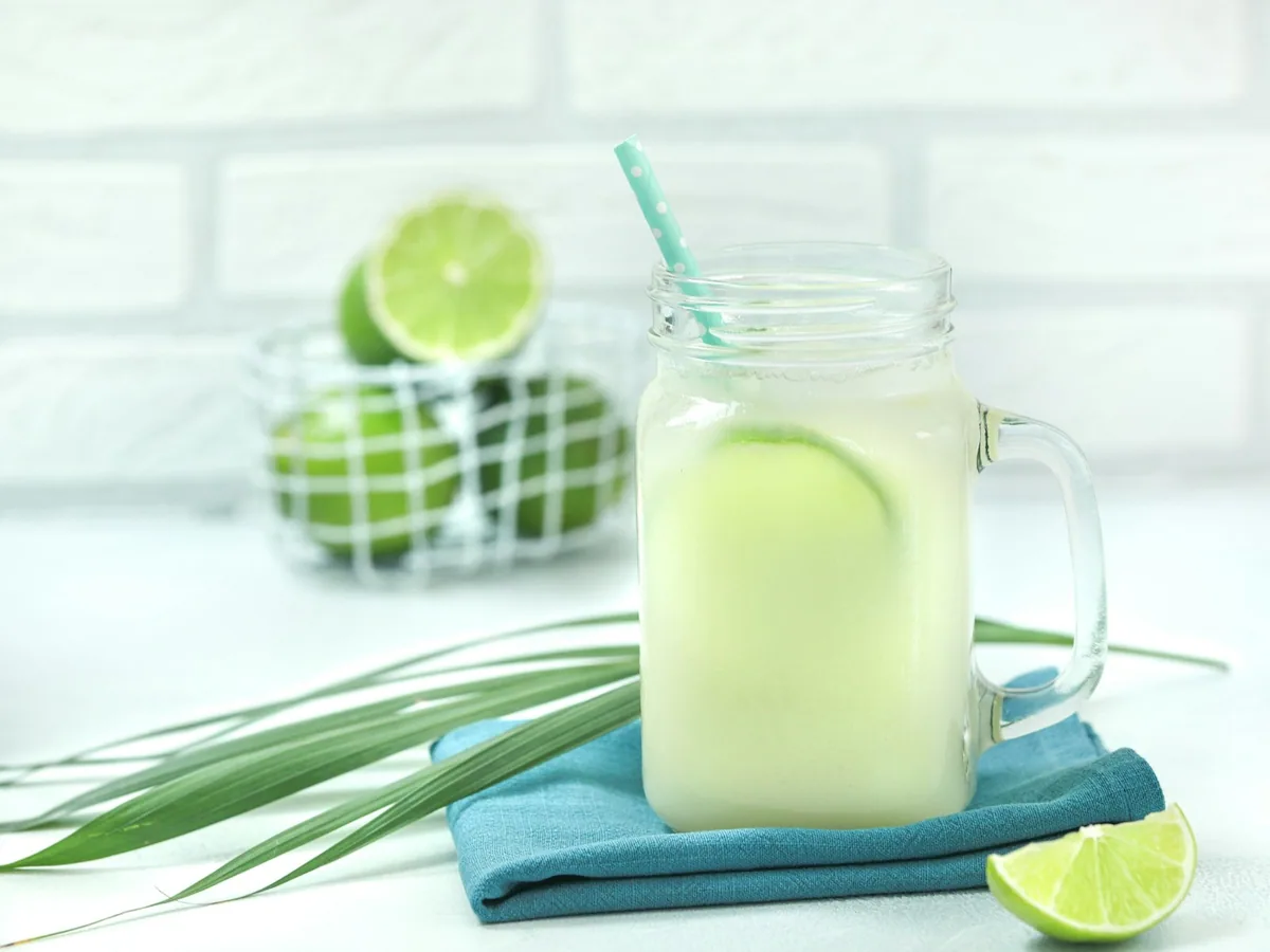 A jar of coconut lemonade with limes