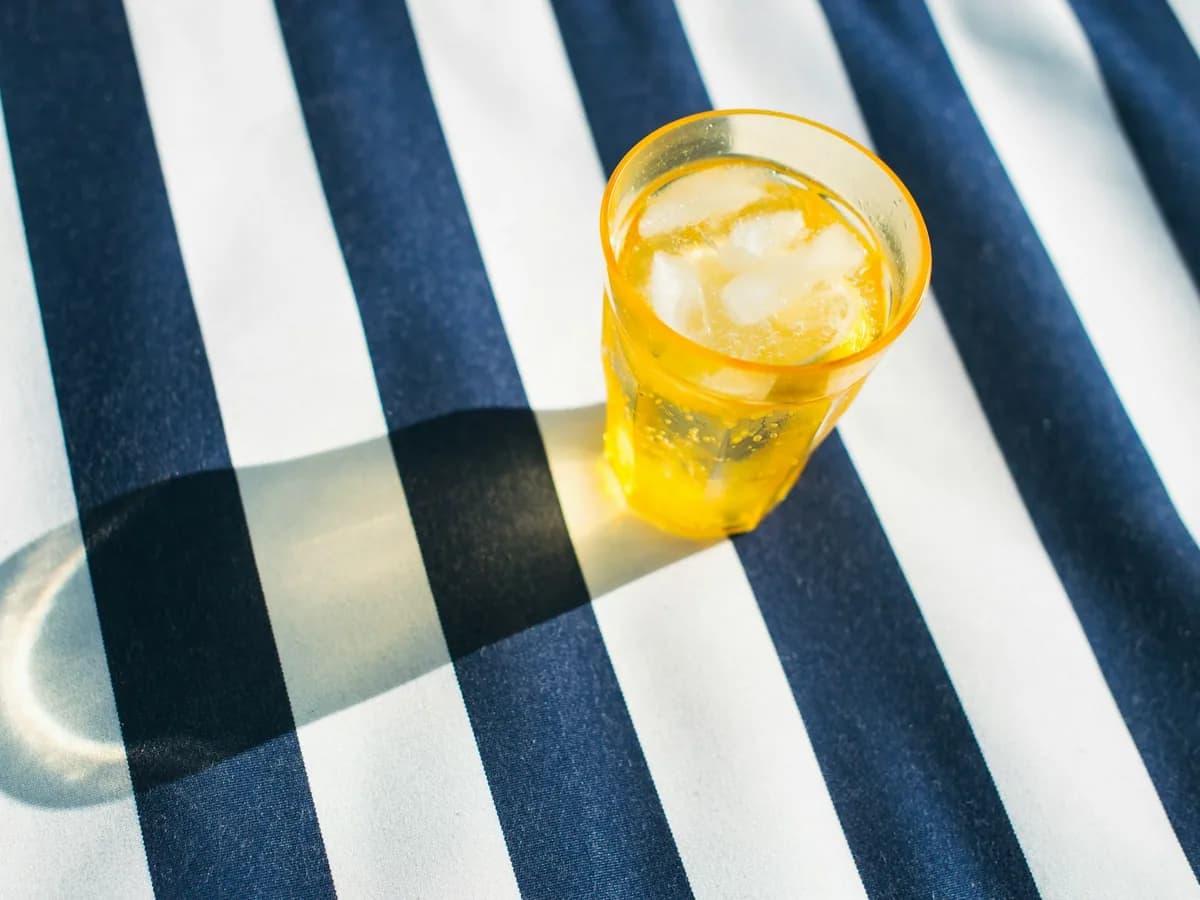 A glass of lemonade with ice on a striped cloth