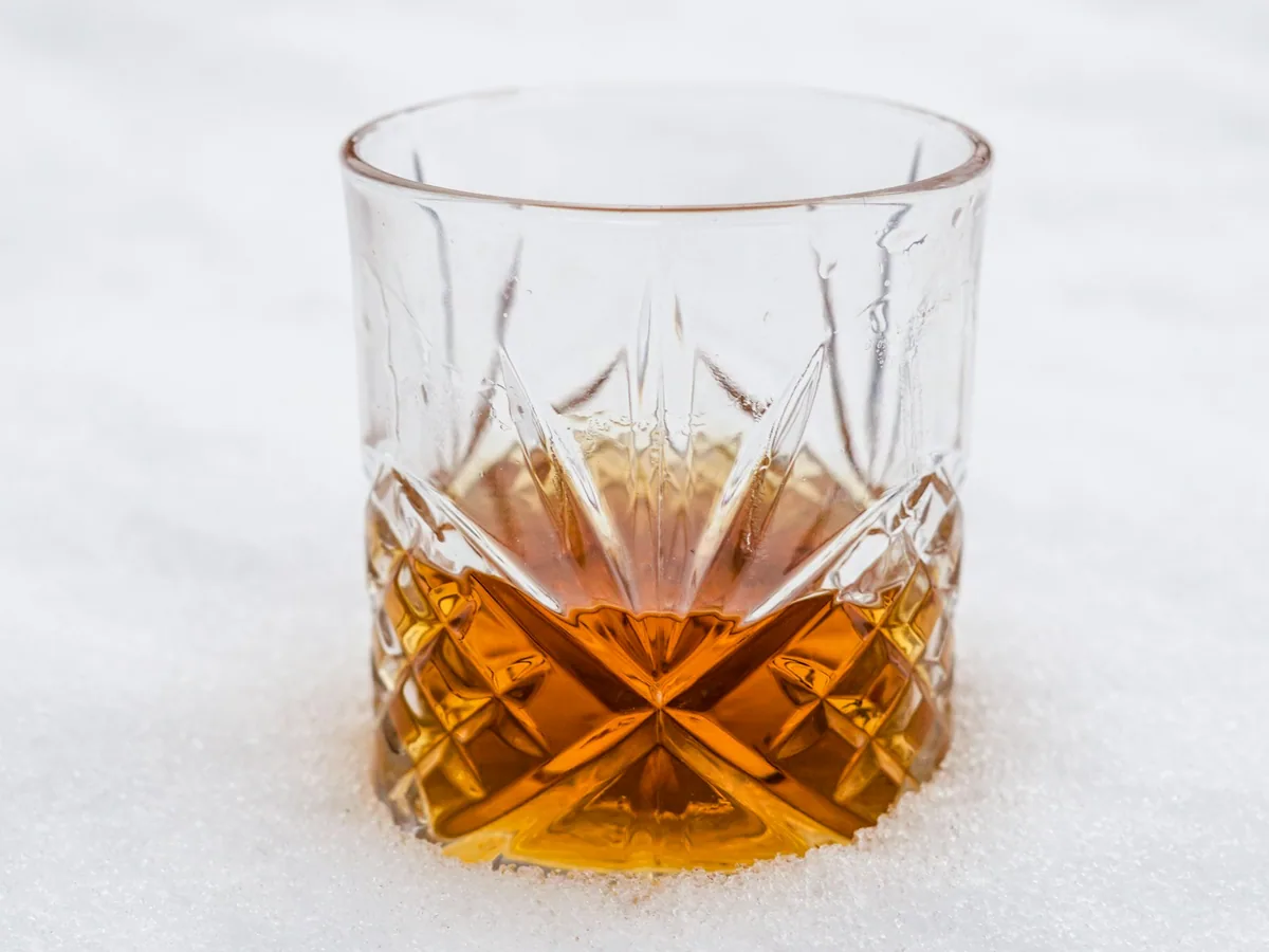 A cut-glass tumbler of whisky against a white ground
