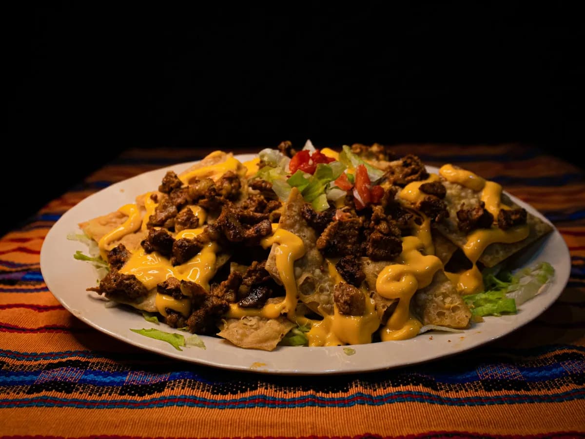 Nachos with meat and melted cheese on a woven cloth