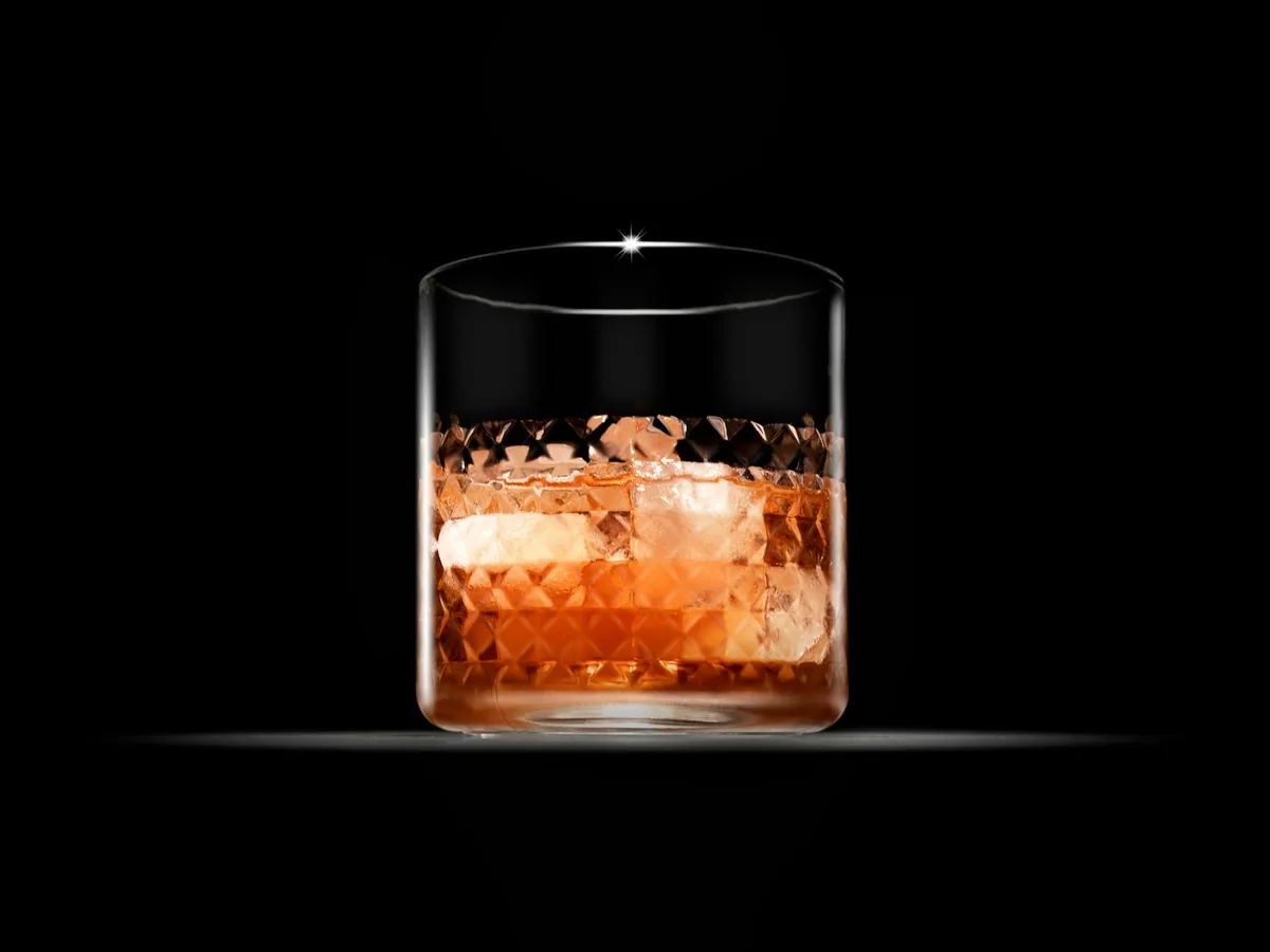 An old fashioned in a short glass against a black ground