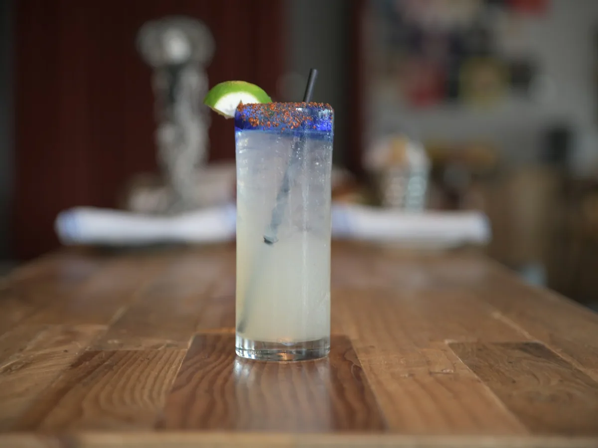 A tall glass with a tequila and lime cocktail