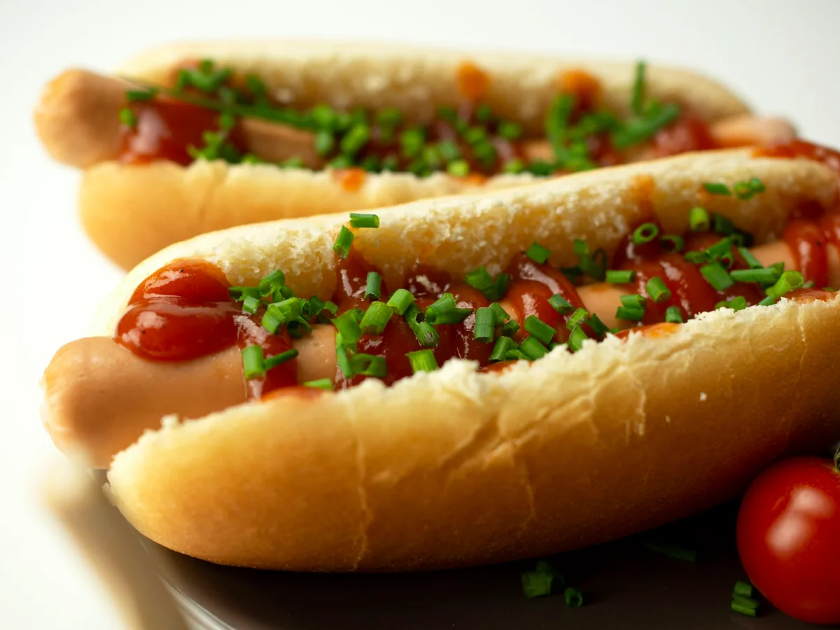 A hot dog with sauce and chives, close up