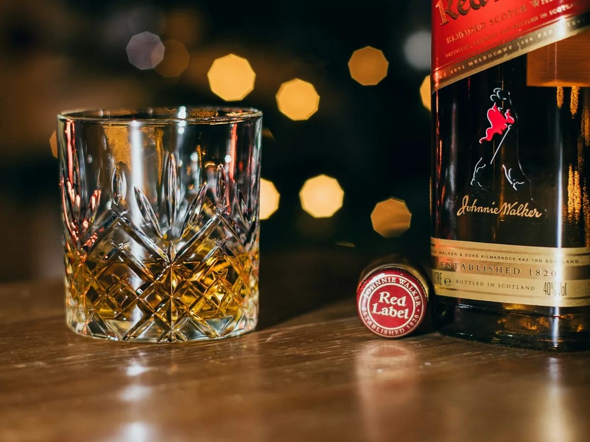 A crystal glass of whisky beside a bottle