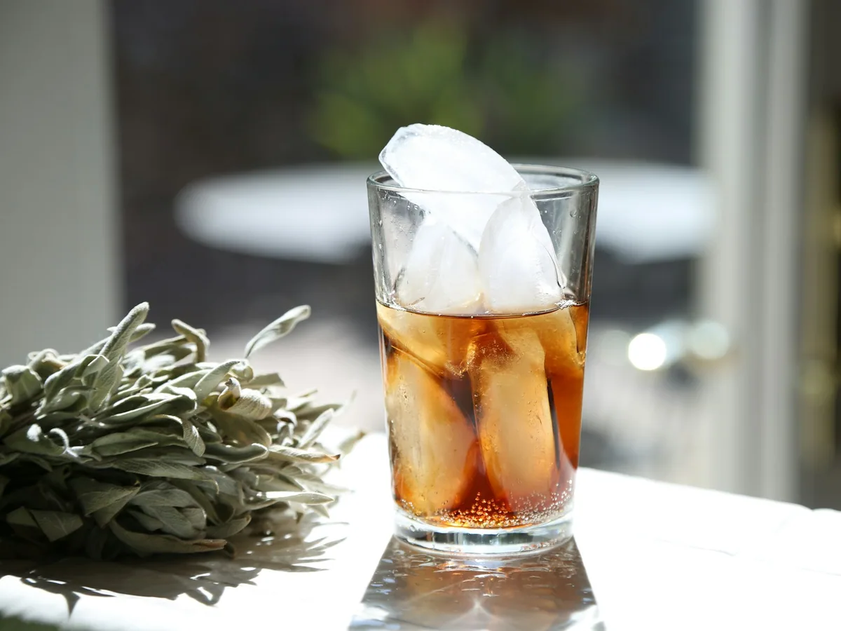 A glass of rum with ice and herbs
