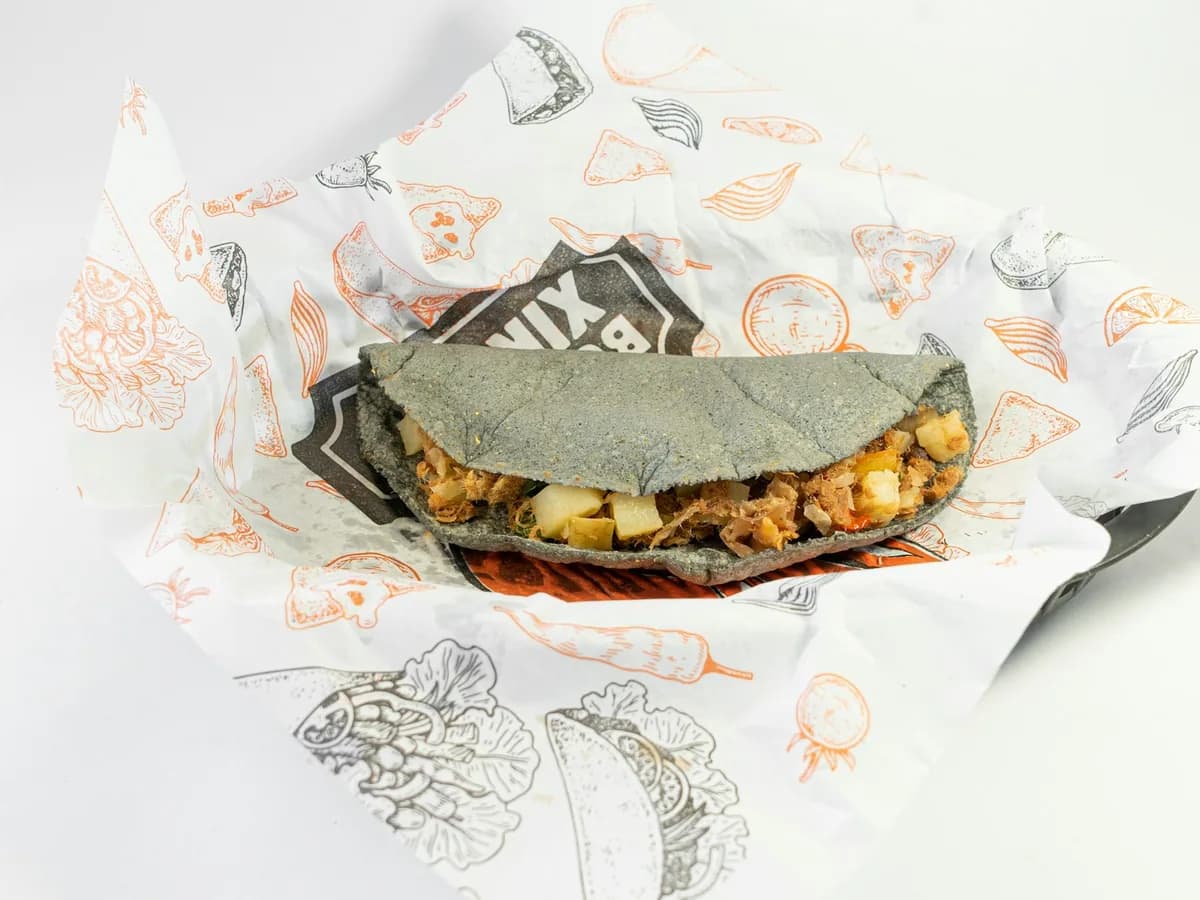 A taco wrapped in paper on a table