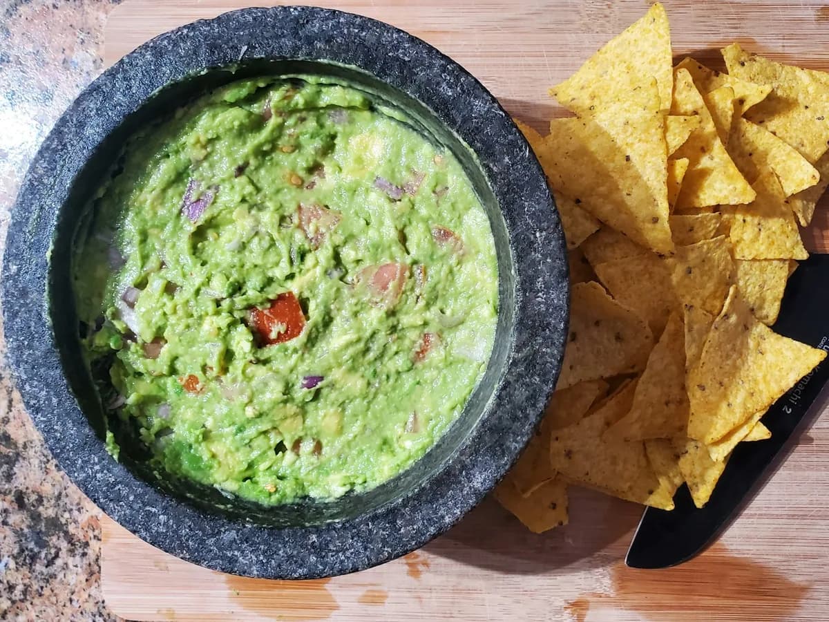 Guacamole in a molcajete with totopos around it
