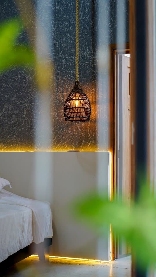 A corner of the Araucana room with a fibre pendant lamp and a plant by the window
