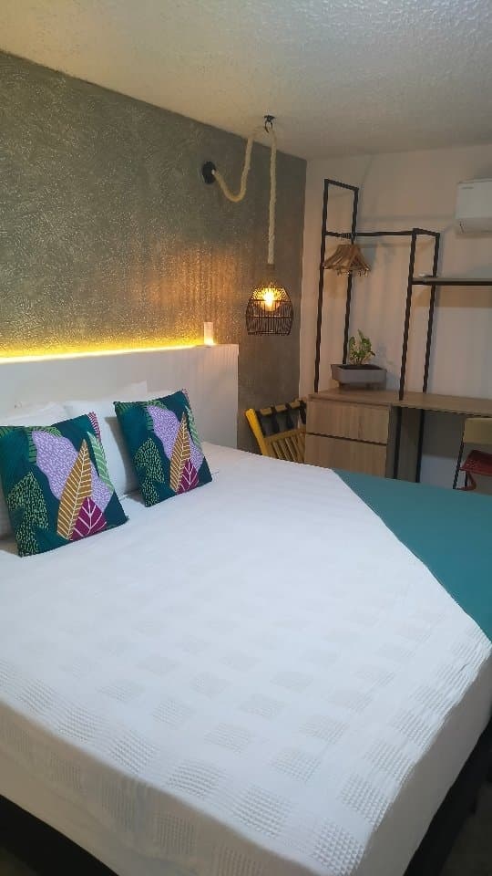 The Exploradora room bed with a patterned cushion and an iron clothes rail behind