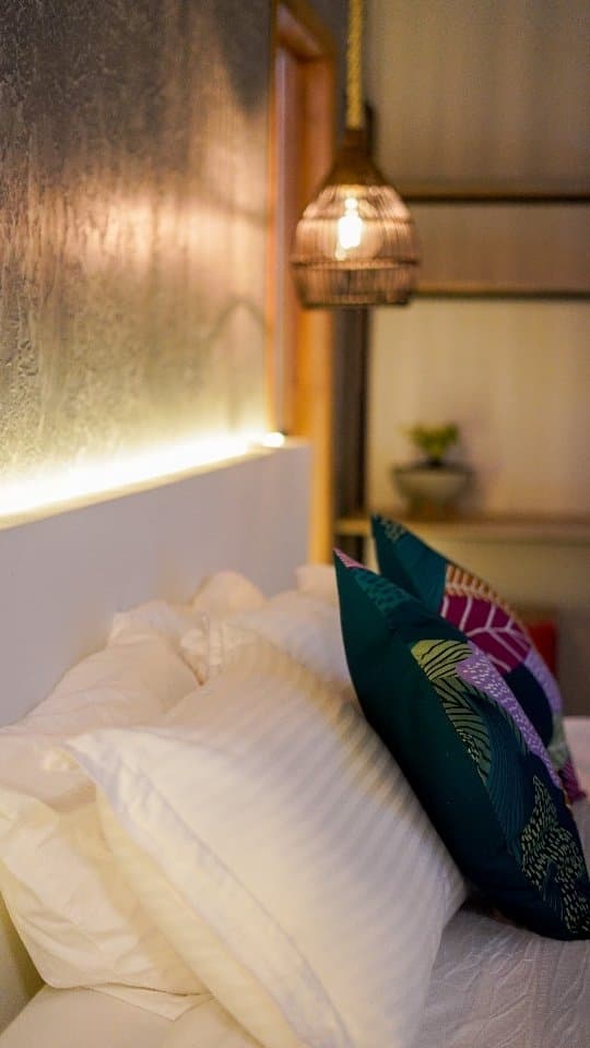 Pillows and a patterned cushion in the La Mixta room under a fibre pendant lamp