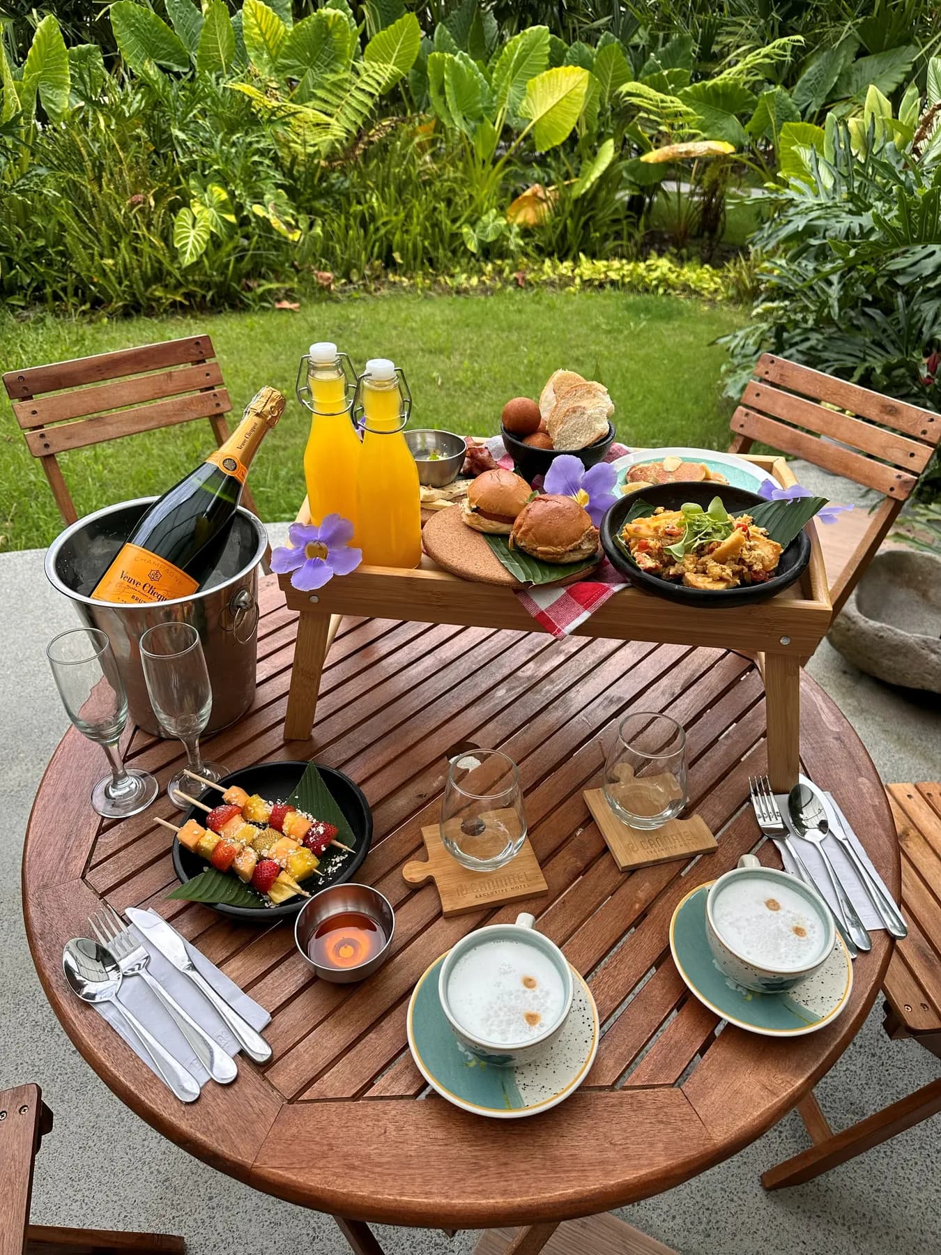 Wooden garden table with a platter of grilled meat, juices and cutlery
