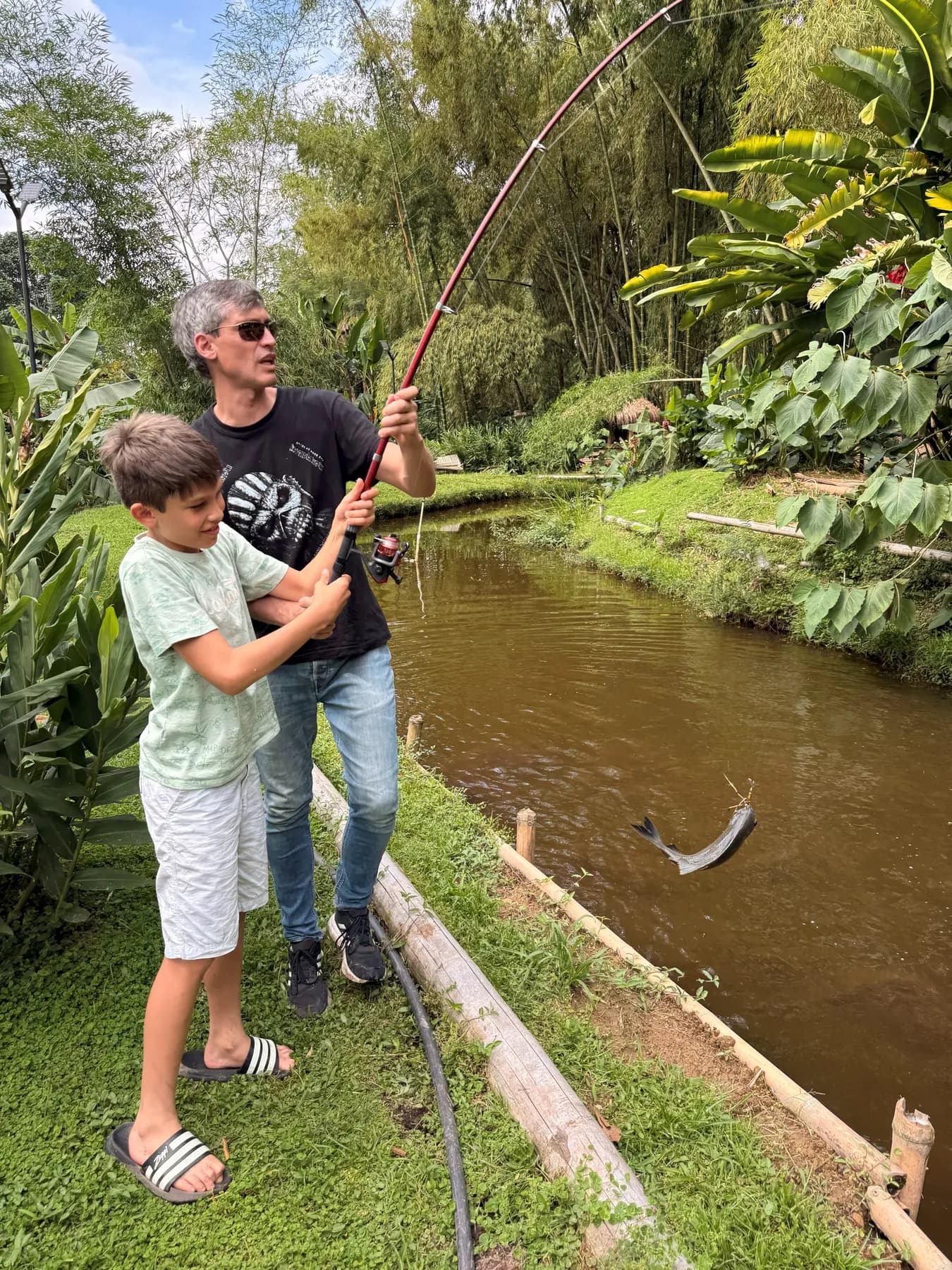 Adult and child fishing with a rod at the lake’s edge